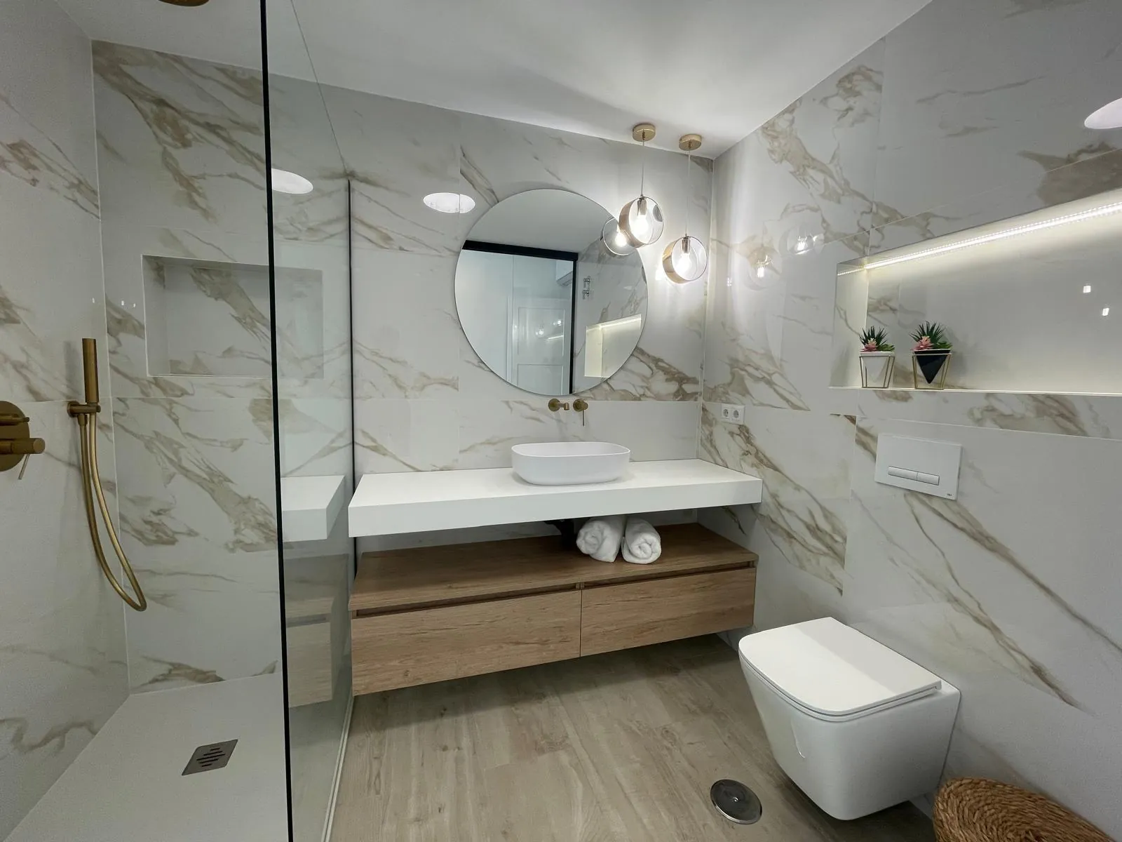 Baño de mármol con ducha de obra, limpio y desinfectado tras el cambio de huésped
