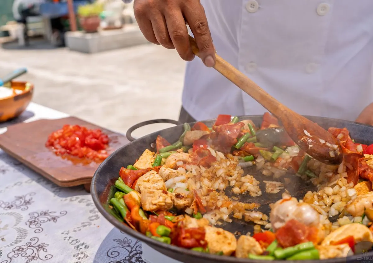 Chef privado cocinando una paella de marisco para los huéspedes en la terraza de una villa